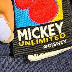 May include: A black and yellow tag with a red Mickey Mouse silhouette and the text "Mickey Unlimited" and "&copy;Disney".