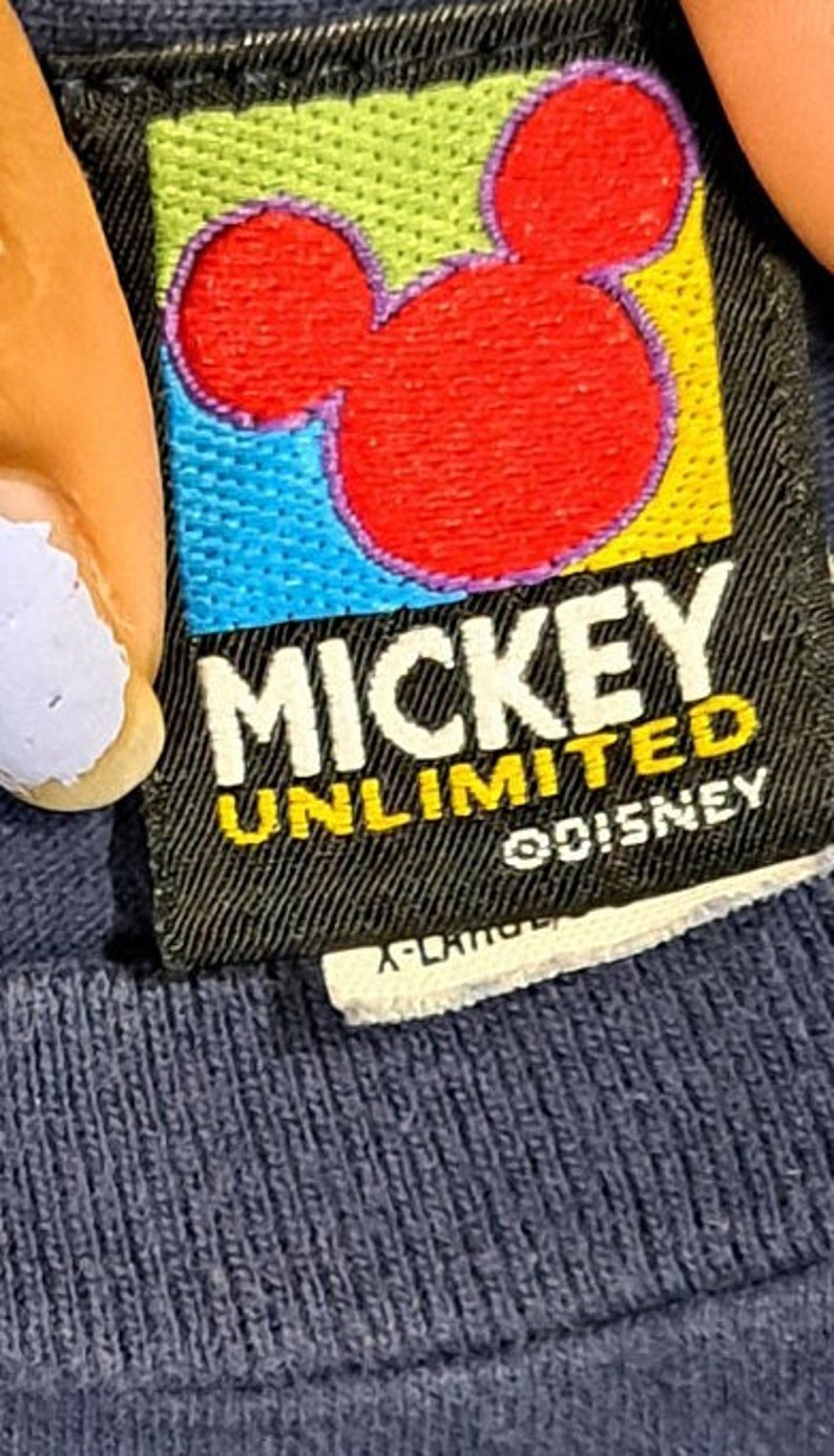 May include: A black and yellow tag with a red Mickey Mouse silhouette and the text "Mickey Unlimited" and "&copy;Disney".