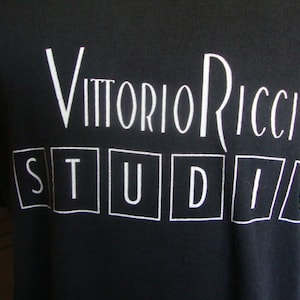 以下が含まれることがあります： 白い文字で「Vittorio Ricci Studio」と書かれた黒いTシャツです。