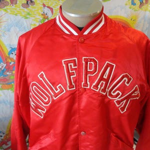 May include: Red satin bomber jacket with white piping and a white embroidered "Wolfpack" on the front.
