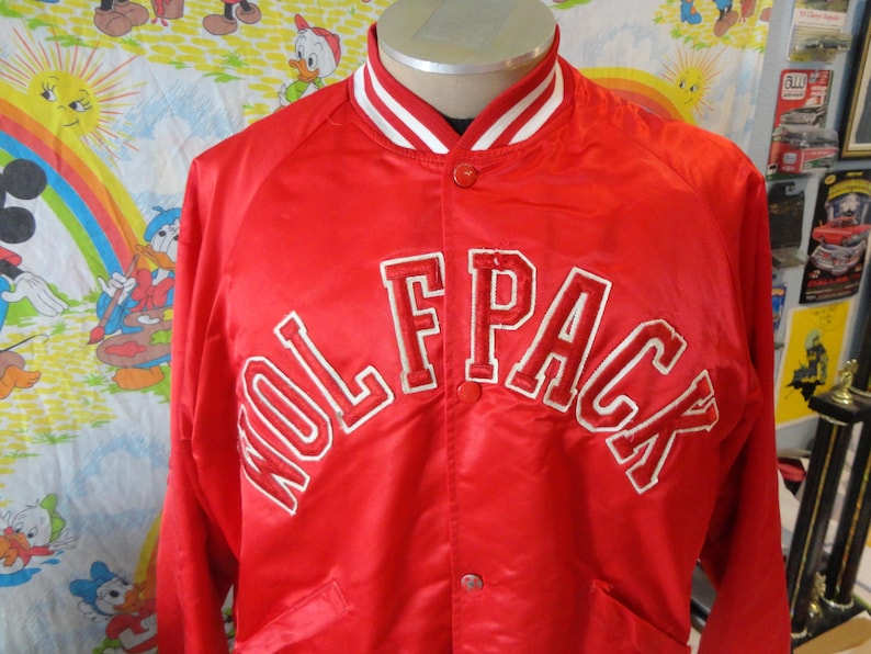 May include: Red satin bomber jacket with white piping and a white embroidered "Wolfpack" on the front.