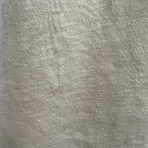 K&ouml;nnte beinhalten: Nahaufnahme eines hellgrauen Stoffes mit einer strukturierten Webart.