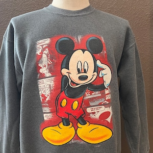 May include: A gray sweatshirt with a red, yellow, and black Mickey Mouse graphic. The graphic features Mickey Mouse with his finger to his chin, thinking. The graphic is surrounded by comic book panels.