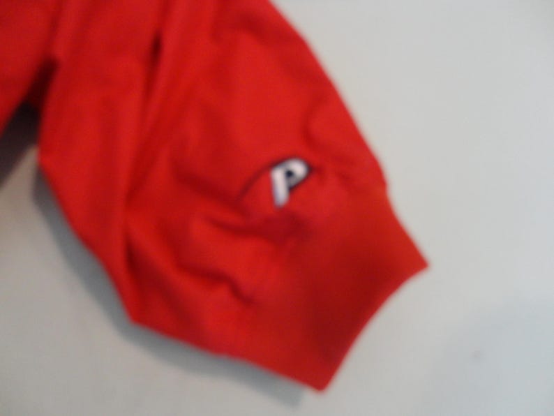 May include: Red short-sleeved shirt with a white "P" logo on the sleeve.
