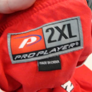 May include: Red and grey Pro Player brand label with the text "2XL" and "Pro Player" with a white and blue logo. The label also says "Made in China".