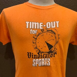 May include: Orange t-shirt with a white graphic that says "Time-Out for Vindicator Sports" and a black and white illustration of a stopwatch.