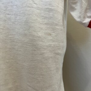 K&ouml;nnte beinhalten: Wei&szlig;es T-Shirt mit roten &Auml;rmelb&uuml;ndchen.