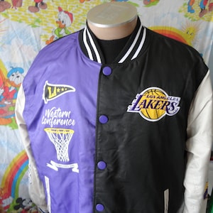 Puede incluir: Chaqueta de satén de dos tonos, dividida verticalmente con paneles morados y negros. El lado morado presenta un gráfico de red de baloncesto y el texto "Western Conference". El lado negro muestra un logotipo de Los Angeles Lakers. Mangas y cuello blancos.