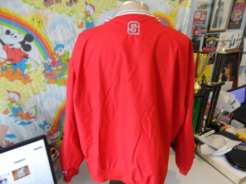 May include: Red windbreaker jacket with a white zip and white trim around the collar and cuffs. The jacket has a white logo on the back that says "80".