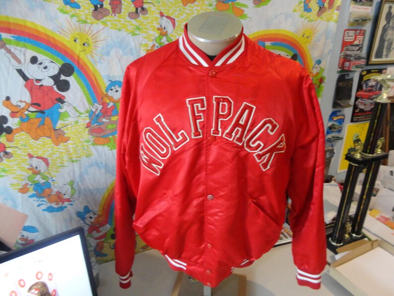 May include: Red satin bomber jacket with white ribbed trim and a white embroidered "Wolfpack" logo on the front.