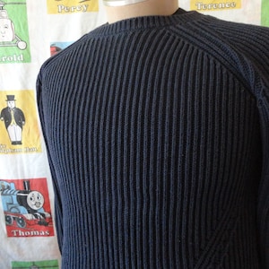 May include: A dark blue ribbed knit sweater with a crew neck and long sleeves.