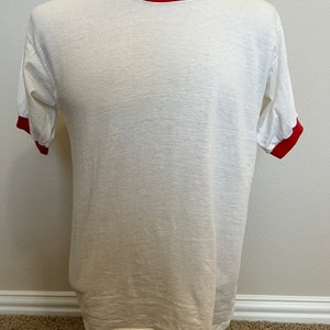 K&ouml;nnte beinhalten: Wei&szlig;es T-Shirt mit rotem Besatz an Kragen und &Auml;rmeln.