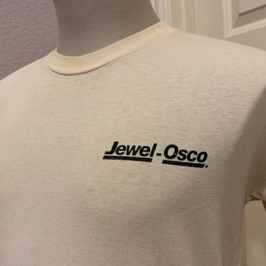 May include: A white t-shirt with a black logo that says "Jewel-Osco" in a retro font.