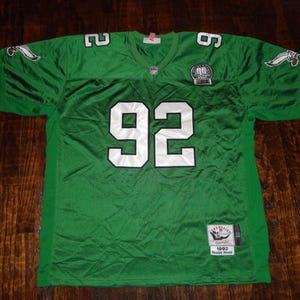 May include: Green football jersey with the number 92 on the front. The jersey has the Philadelphia Eagles logo on the sleeves and a patch that says "1992 Super Bowl Champs".