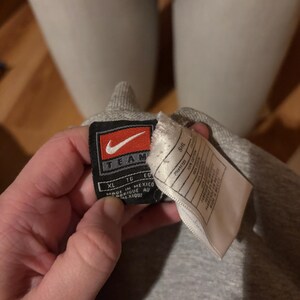May include: Gray Nike Team sweatshirt tag with a white background. The tag shows the size XL, TG, EG, and the text "Made in Mexico" and "Fabrique au Mexique".