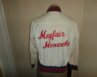May include: White varsity jacket with red and blue trim. The back of the jacket has "Mayfair Monarchs" embroidered in red.