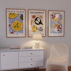 May include: Three framed illustrations of food with the titles "Pesto Penne Rome", "Food Market Paris", and "Crepes Paris". The illustrations are in a minimalist style with a blue and white checkered background.