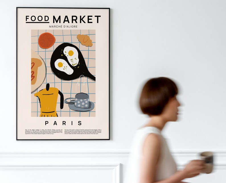 May include: A poster with a black frame featuring a colorful illustration of breakfast food, including eggs, bread, coffee, and a croissant. The poster has the text "FOOD MARKET" and "MARCHE D'ALIGRE" in black text. The poster also has the text "PARIS" in black text.