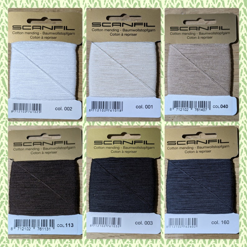 May include: Six spools of cotton mending thread in various colors, including white, beige, brown, black, and gray. Each spool is labeled with the brand name "SCANFIL" and the color number.