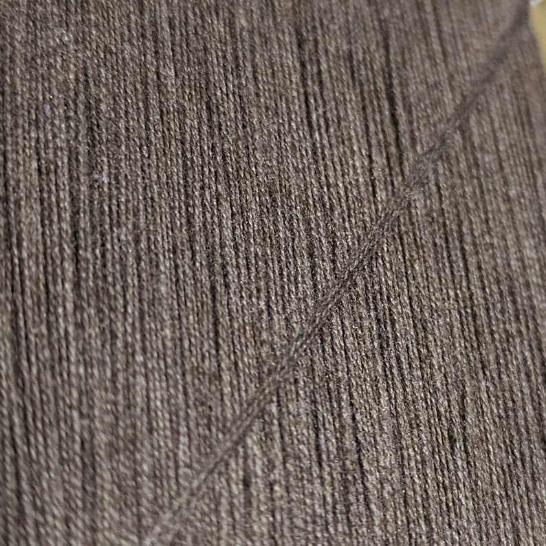 May include: Close-up of a dark brown yarn with a subtle sheen. The yarn is tightly woven and has a smooth texture.