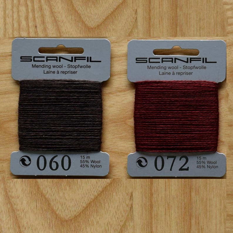 May include: Two Scanfil mending wool cards, one dark brown labelled 060 and one deep red labelled 072. Each card contains 15 metres of 55% wool and 45% nylon thread. The packaging displays the brand name, material composition, and colour code.