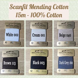 May include: Six spools of Scanfil Mending Cotton, each 15 meters long and 100% cotton. The colors are white, cream, beige, brown, black, and dark grey. Each spool has a label with the brand name, color, and color code.