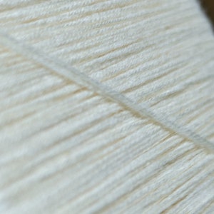 May include: Close-up of a white yarn skein, showing the individual strands of yarn.