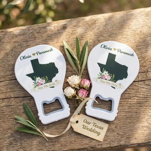 May include: Two white bottle openers featuring a dark green silhouette of the state of Texas, floral accents, and the text Olivia Paramesh May 9th 2026. A small beige tag attached with ribbon reads Our Texas Wedding, accompanied by dried flowers.