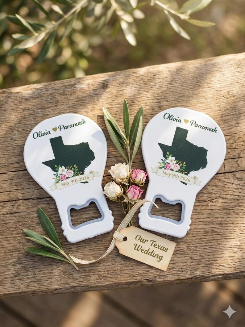 May include: Two white bottle openers featuring a dark green silhouette of the state of Texas, floral accents, and the text Olivia Paramesh May 9th 2026. A small beige tag attached with ribbon reads Our Texas Wedding, accompanied by dried flowers.