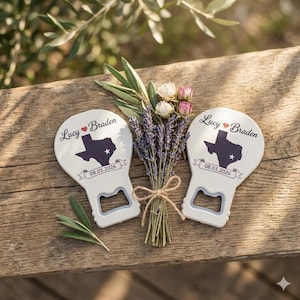 Könnte beinhalten: Zwei weiße Flaschenöffner mit Texas-Umriss und den Namen "Lucy" und "Braden". Das Datum "08.01.2026" ist auf einem Banner aufgedruckt. Ein Bouquet aus Lavendel und Blumen befindet sich in der Mitte, auf Holz.
