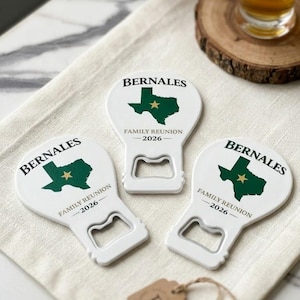 May include: Three white bottle openers with a Texas-shaped graphic in green and a gold star. The text "BERNALES" and "FAMILY REUNION 2026" are printed on each opener. A small brown tag with the letter "E" is also visible.