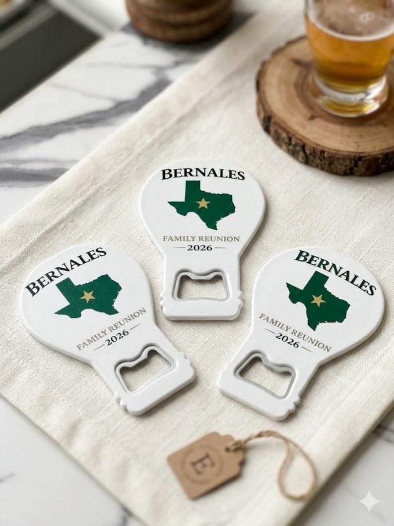 May include: Three white bottle openers with a Texas-shaped graphic in green and a gold star. The text "BERNALES" and "FAMILY REUNION 2026" are printed on each opener. A small brown tag with the letter "E" is also visible.