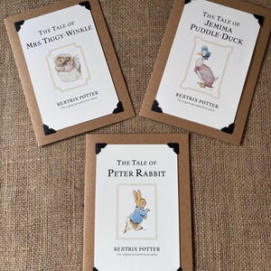 Könnte beinhalten: Drei Beatrix Potter-Buchcover: "The Tale of Mrs. Tiggy-Winkle", "The Tale of Jemima Puddle-Duck" und "The Tale of Peter Rabbit". Jedes Cover zeigt eine Charakterillustration und ist vor einem cremefarbenen Hintergrund mit braunem Rand.