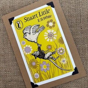 Könnte beinhalten: Ein Vintage-Buchcover für "Stuart Little" von E.B. White, mit einem gelben Hintergrund mit floralen Designs und einer Illustration eines Vogels, der eine Maus trägt. Das Buch ist auf einem weißen Rahmen und einer braunen Karte montiert.
