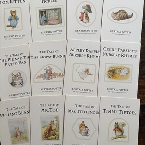 May include: A collection of twelve Beatrix Potter books with cream-coloured covers, each featuring a unique colour illustration of an animal character and the title printed in black text. The titles include The Tale of Tom Kitten, Ginger and Pickles, Benjamin Bunny, Miss Moppet, The Pie and the Patty-Pan, The Flopsy Bunnies, Appley Dapply, Cecily Parsley, Pigling Bland, Mr. Tod, Mrs. Tittlemouse, and Timmy Tiptoes.