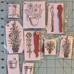 May include: Ten clear plastic bags with white card stock inserts containing rubber stamps with floral and plant designs. The stamps are labeled with numbers 33 through 41 and the word "HALOS".