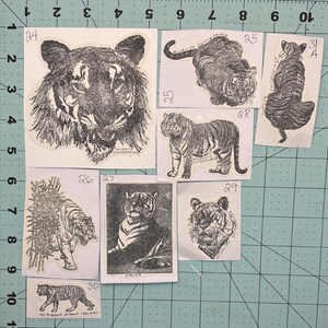 May include: A collection of ten rubber stamps featuring black and white images of tigers. The stamps are numbered 24 through 31 and are arranged in a grid pattern. The stamps are all from the same company, Wildlife Enterprises.