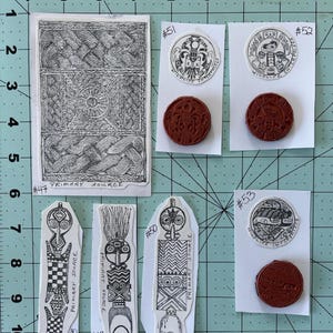 May include: A collection of eight vintage rubber stamps featuring wildlife and nature designs. The stamps are arranged on a white background with black grid lines. The stamps are numbered 47 through 53. The stamps feature images of a woven pattern, a bird, a fish, and a stylized human figure.