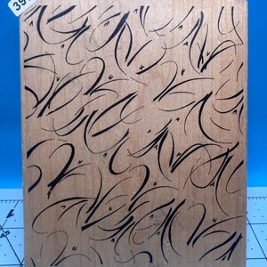 May include: A wooden stamp with a repeating black abstract design. The stamp has a light brown surface and a rectangular shape. A small white sticker with the number "3970" is in the upper left corner.