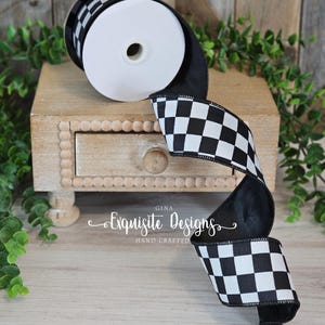 May include: A roll of black and white checkered ribbon. The ribbon is displayed on a small wooden stand with a drawer. The text "Gina Exquisite Designs Hand Crafted" is visible on the stand.