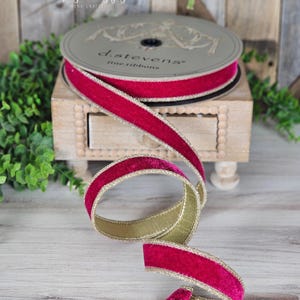Op de afbeelding: Een spoel d. stevens fijn lint met een rijke magenta fluwelen voorkant en gouden rand. Het lint wordt getoond op een kleine houten kist. De spoel is grijs met de tekst "d. stevens fine ribbons". Handgemaakt door Gina Exquisite Designs.