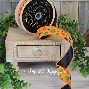 Puede incluir: Cinta naranja con lunares verdes, morados y naranjas, y reverso de satén negro. La cinta está en una bobina con la etiqueta "D'Lux Ribbon". La imagen también muestra "Exquisite Designs Hand Crafted".