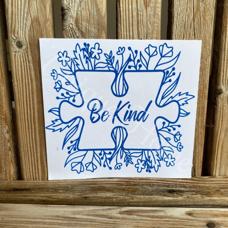 May include: Blue vinyl decal with a puzzle piece design and the words "Be Kind" surrounded by a floral border.