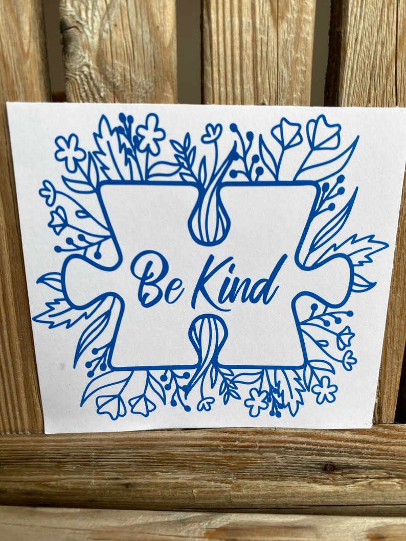 May include: Blue puzzle piece with the words "Be Kind" inside, surrounded by a floral design.