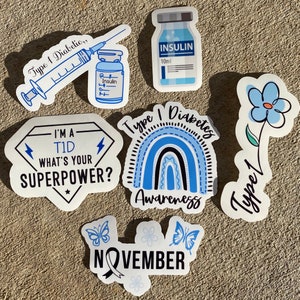 May include: A set of seven stickers featuring blue and white designs related to Type 1 Diabetes awareness. The stickers include a syringe, an insulin bottle, a rainbow, a flower, a diamond with the text "I'm a T1D What's your superpower?", and two butterflies with the text "November".
