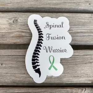 May include: White sticker with a black silhouette of a spine, a green ribbon, and the text "Spinal Fusion Warrior".