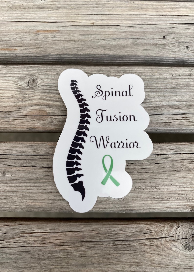 May include: White sticker with a black silhouette of a spine, a green ribbon, and the text "Spinal Fusion Warrior".