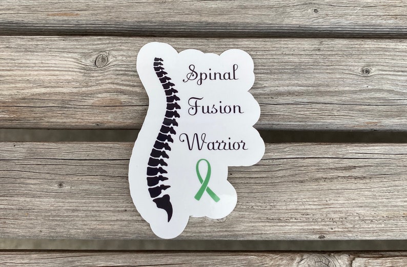 May include: White sticker with a black silhouette of a spine and the text "Spinal Fusion Warrior" with a green ribbon.