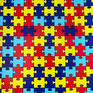 May include: A repeating pattern of puzzle pieces in blue, red, yellow, and light blue. The puzzle pieces are arranged in a grid pattern.