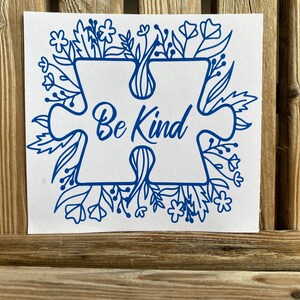 May include: Blue puzzle piece with the words "Be Kind" inside, surrounded by a floral design.